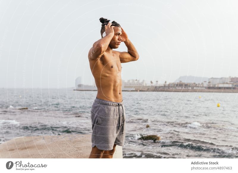 Schwarzer Sportler beim Musikhören am Meer MEER Strandpromenade meloman Gesang Gesunder Lebensstil Melodie Küste Zeitvertreib Mann Freizeit Körper zuhören