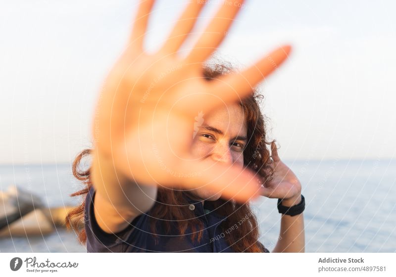 Lächelnde Frau, die eine Stopp-Geste zeigt stoppen gestikulieren Porträt Strand Himmel Handfläche zeigend Nahaufnahme Sonnenlicht Lifestyle schön Freizeit