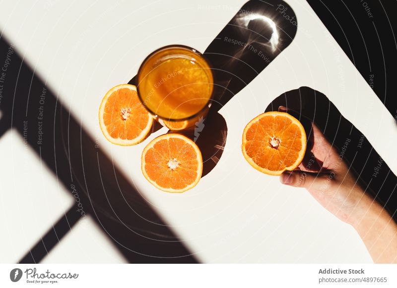 Crop-Frau nimmt Orangensaft Saft orange Glas Morgen Diät Vitamin C gesundes Getränk sonnenbeschienen Tisch Hälfte drücken Entzug frisch Frucht Frühstück reif