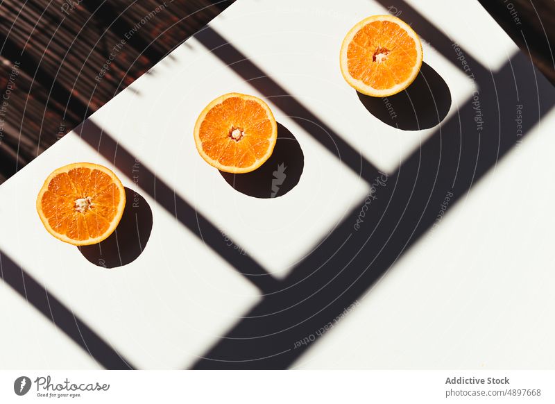 Ausgepresste Orangenhälften auf dem sonnendurchfluteten Tisch orange Zusammensetzung Morgen drücken Saft Diät Schatten Reling frisch Sonnenlicht Hälfte Vitamin
