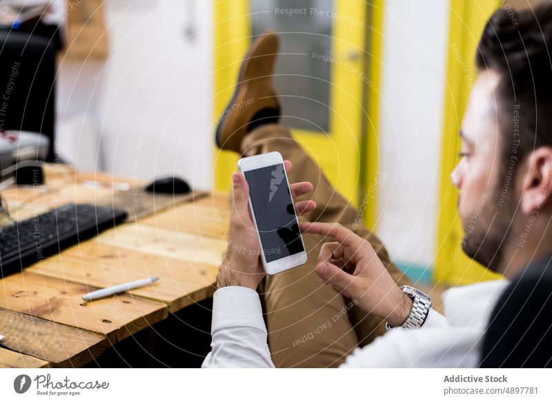 Mann, der im Büro auf seinem Smartphone surft Arbeit online Browsen Projekt Business Arbeitsplatz Textnachricht schwarzer Bildschirm benutzend Funktelefon