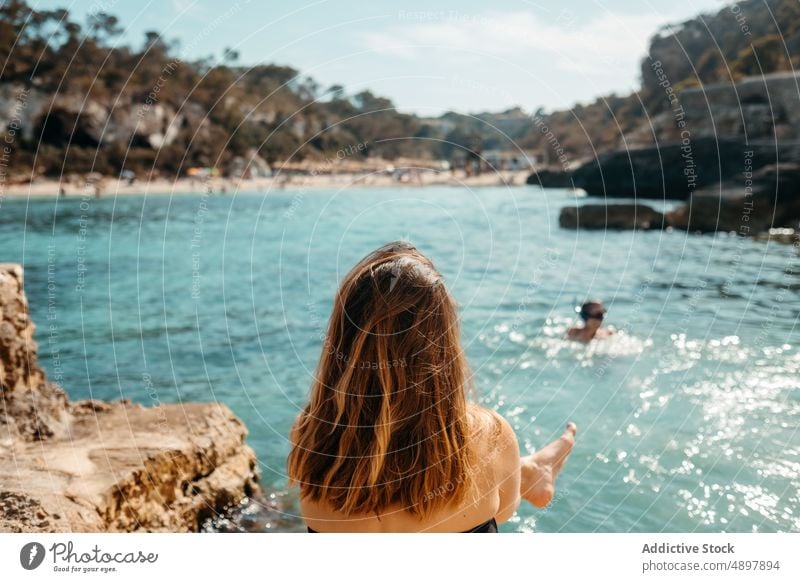 Anonyme Frau sonnt sich an der Felsenküste und bewundert das Meer sich[Akk] entspannen MEER Strand Meeresufer bewundern Feiertag Sonnenbad genießen Urlaub