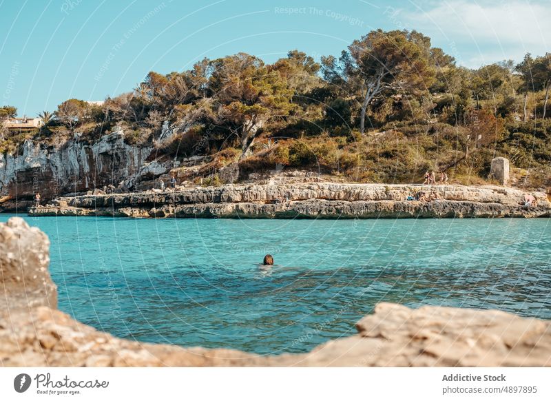 Anonyme Frau schwimmt an felsiger Küste Schwimmsport sich[Akk] entspannen MEER Strand Meeresufer bewundern Feiertag genießen Urlaub Erholung Natur jung