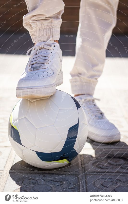 Anonymer Mann mit Fuß auf Fußball jung Schuh Stehen Fußweg Spieler weiß Bein Schatten Lifestyle Ball Mode Freizeit Sport modisch attraktiv Großstadt Sportler