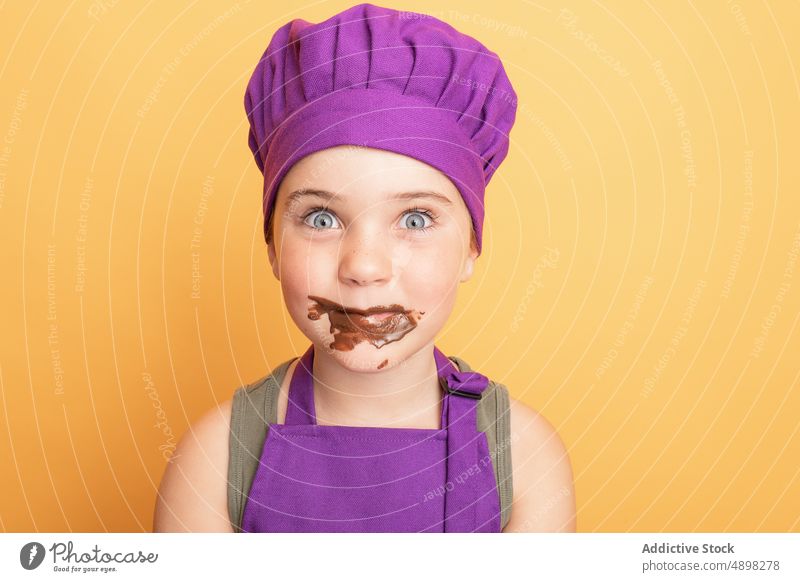 Lustiges Mädchen mit Schokolade überzogen Kind Küchenchef unordentlich süß Koch Helfer kulinarisch Frau schelmisch Leckerbissen Mund geöffnet Erstaunen erstaunt