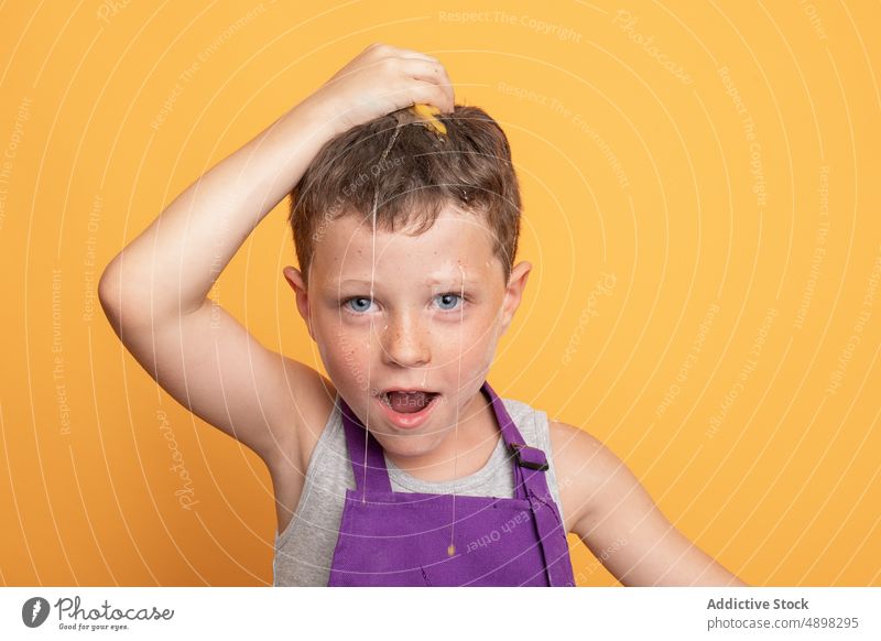 Fröhlicher Junge schlägt Ei auf dem Kopf auf Kind Küchenchef Koch Helfer kulinarisch Pause Spaß haben schelmisch natürlich widerspenstig Produkt Bestandteil
