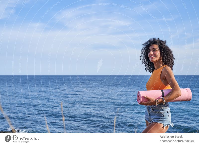 Hispanische Frau mit Yogamatte am Meeresufer Unterlage Ufer MEER Gesunder Lebensstil Training Hobby Küste Zeitvertreib Vorschein Stil Sommer feminin Aktivität