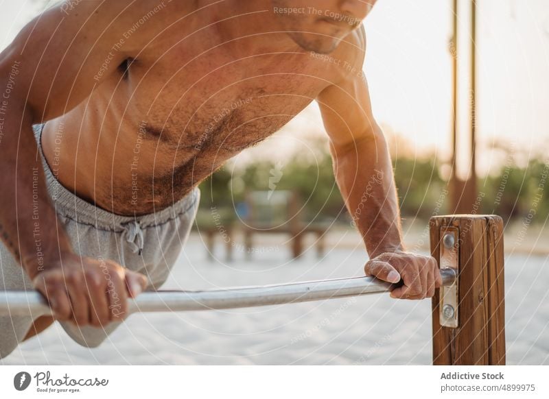 Anonymer Sportler, der Liegestütze an der Stange macht hochschieben Übung Mann Training Muskel calisthenics Bestimmen Sie stark Strand hispanisch männlich