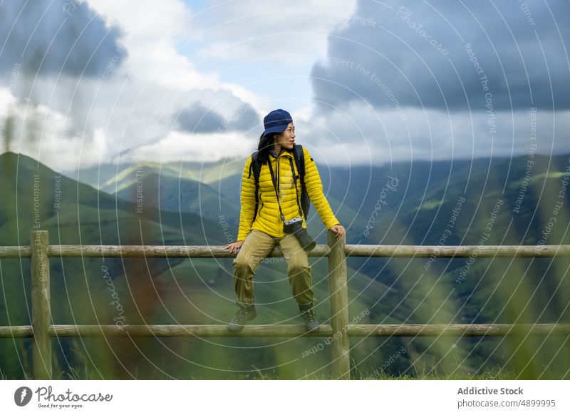 Porträt eines schönen asiatischen Mädchens, das auf einem Geländer mit grünem Chinesisches Mädchen Spanien aktiv Rucksack Windstille Fotokamera Verschlussdeckel