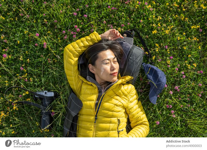 Porträt eines schönen asiatischen Mädchens, das auf dem Gras liegt und die Hand hält Chinesisches Mädchen Spanien aktiv Rucksack Windstille Fotokamera
