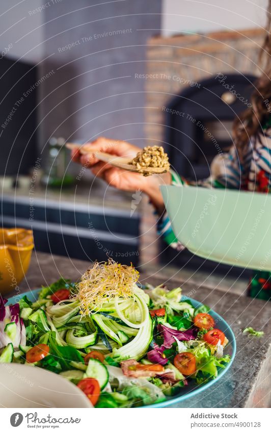 Frau gibt Quinoa in Salat Koch Salatbeilage Veganer Küche gesunde Ernährung kulinarisch Bestandteil selbstgemacht Produkt Mittagessen Vitamin Salatgurke Gemüse