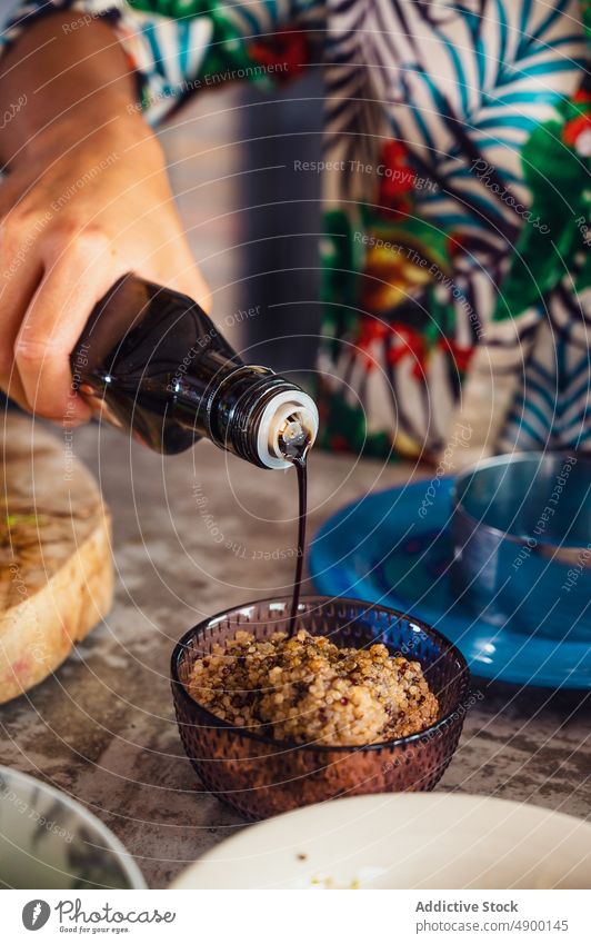 Crop-Frau gibt Sojasauce in Quinoa Koch eingießen vorbereiten Schalen & Schüsseln Küche Veganer gesunde Ernährung hinzufügen heimwärts kulinarisch Bestandteil