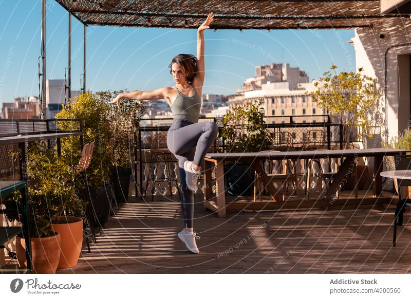 Sportlerin beim Training auf der Terrasse eines Gebäudes Übung sportlich Gesunder Lebensstil üben Hobby Großstadt Bein angehoben Arm angehoben Gleichgewicht