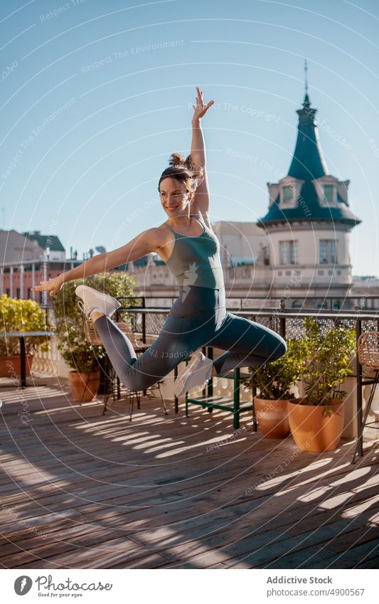 Sportlerin springt beim Training auf die Terrasse Übung Glück Frau Lächeln Gesunder Lebensstil üben springen Bestimmen Sie sich[Akk] bewegen Arm angehoben