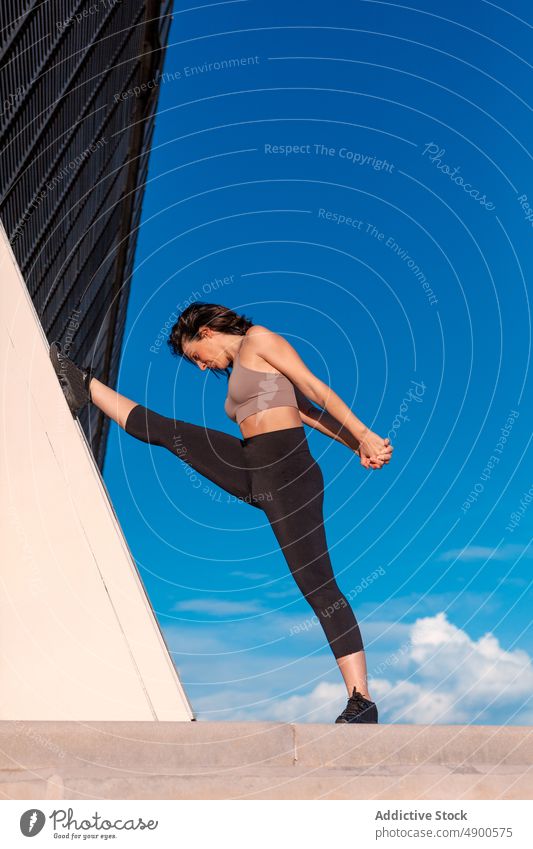 Flexible Frau streckt ihr Bein auf der Straße Sportlerin Übung Aufwärmen Dehnung Training üben Bein angehoben Hobby ausführen Körper Wand Split Figur Waffen