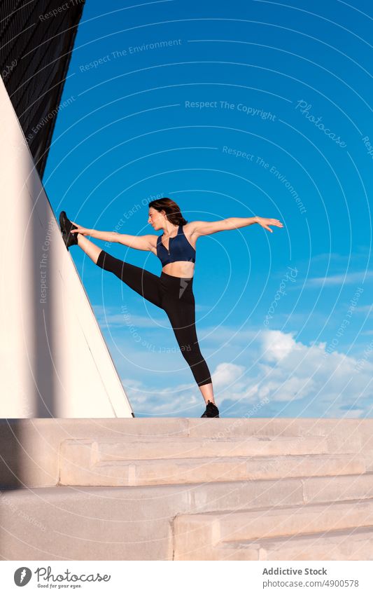 Flexible Frau streckt ihr Bein auf der Straße Sportlerin Übung Aufwärmen Dehnung Training üben Bein angehoben Hobby ausführen Körper Wand Split Figur