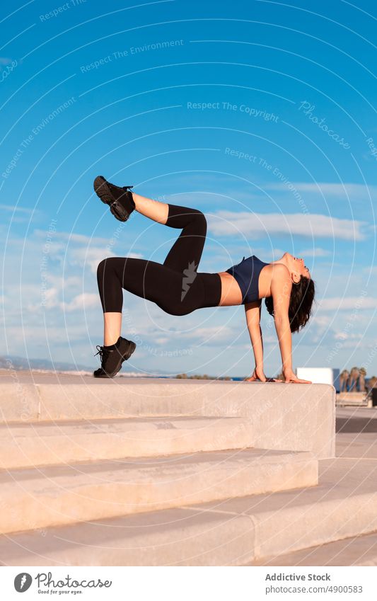 Positive Frau beim Sport auf der Straße Sportlerin Übung Training Gesunder Lebensstil üben Krabbe Hobby Bein angehoben Ausdauer Inhalt Körper Figur beweglich