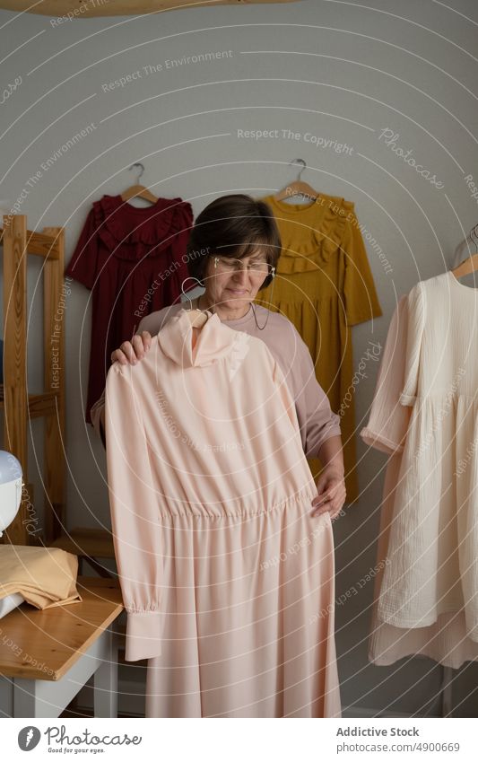 Ältere Näherin zeigt handgefertigtes Kleid Frau zeigen Atelier Arbeit Kleinunternehmen Porträt Handwerk Nähmaschine reif Lebensmitte Damenschneiderin