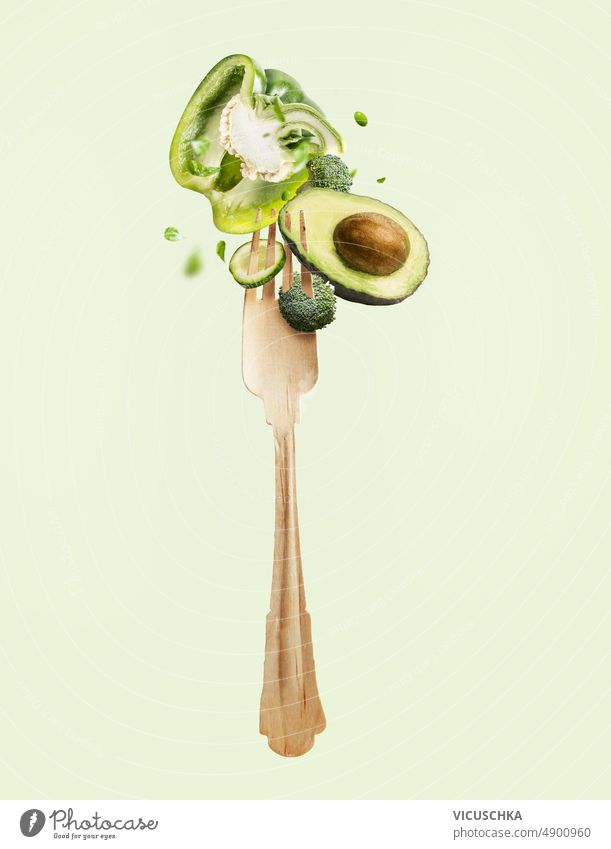 Fliegende Gabel mit grünem Gemüse Salatzutaten fliegen Schweben von Lebensmitteln Diät Entzug Salatbeilage Zutaten Paprika Avocado Brokkoli Salatgurke
