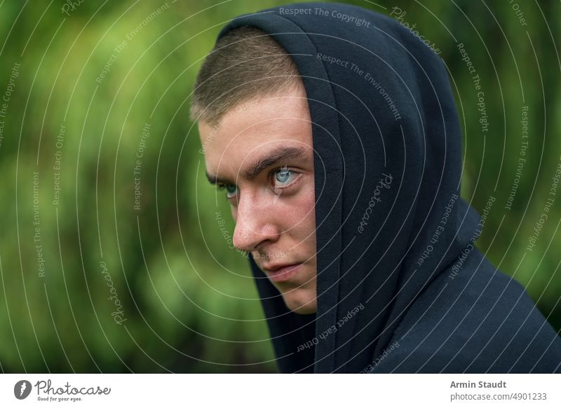 Porträt eines jungen ernsten Mannes mit Kapuzenpulli Aussehen Teenager Blick männlich schön lässig Kaukasier im Freien selbstbewusst Model Lifestyle Sonnenlicht