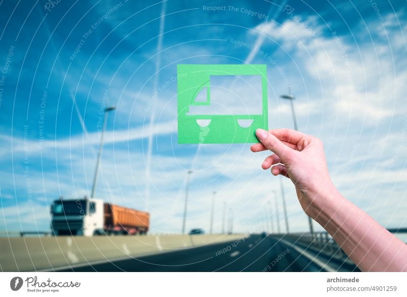 Hand hält grünes Logistiksymbol gegen Autobahn logistisch Verkehr Öko Klima Konzept Ökologie Lastwagen Zukunft Erhaltung Versand reisen Energie Umwelt