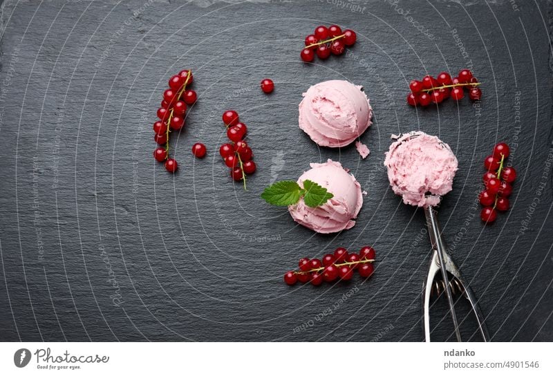 Rosa Eiskugeln auf einer schwarzen Steinplatte, daneben rote Johannisbeeren, Ansicht von oben Speiseeis Lebensmittel Dessert süß Baggerlöffel Sahne kalt Vanille