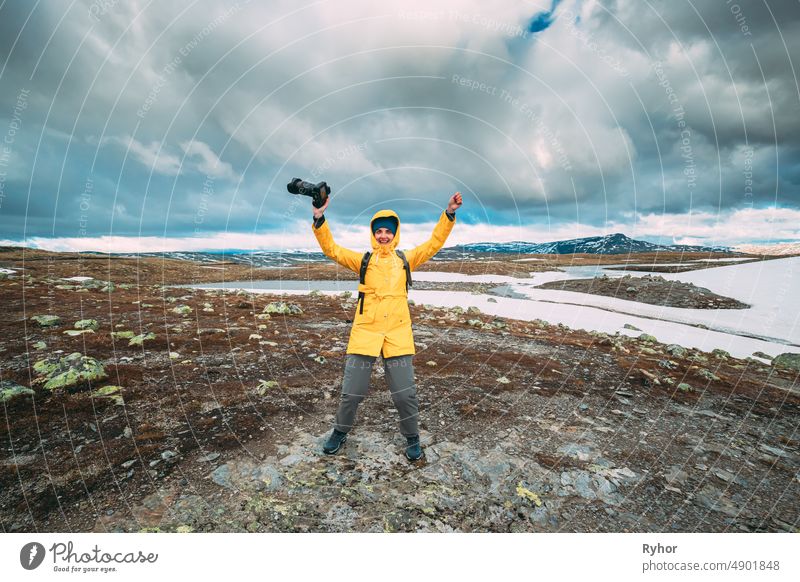 Aurlandsfjellet, Norwegen. Happy Young Woman Tourist Traveler Photographer With Camera Walking Near Aurlandsfjellet Scenic Route Road. Aktiver Lebensstil in der norwegischen Natur