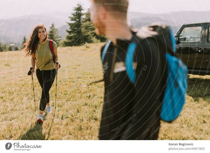 Lächelndes Paar beginnt mit Rucksäcken über grüne Hügel zu wandern aktiv Aktivität Erwachsene Abenteuer Rucksack Backpacker Rucksacktourismus Freund Kaukasier