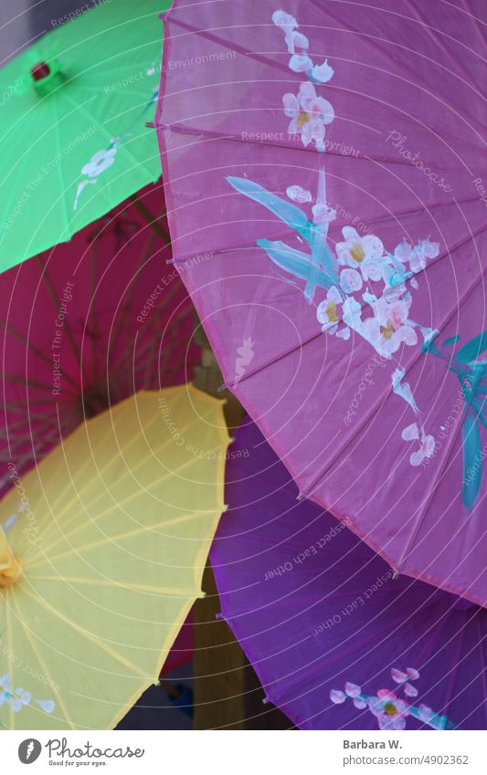 Eine Sammlung von handbemalten asiatischen Sonnenschirmen aus Reispapier. Regenschirme gelb rosa purpur rot grün bunt dekorativer Sonnenschirm Dekor