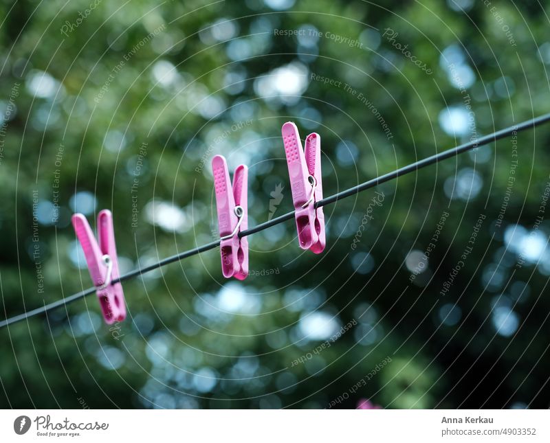 Drei rosafarbene Wäscheklammern an der Wäscheleine vor grünem Hintergrund drei hängen lassen Klammer aufgespannt Wäsche waschen Waschtag Häusliches Leben