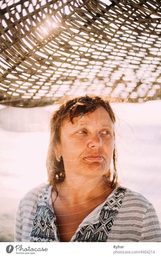 Erwachsene kaukasische Frau entspannt posiert unter Strand Sonnenschirm auf Sonnenuntergang. Urlaub am Meer Ozean Erwachsener attraktiv authentisch schön