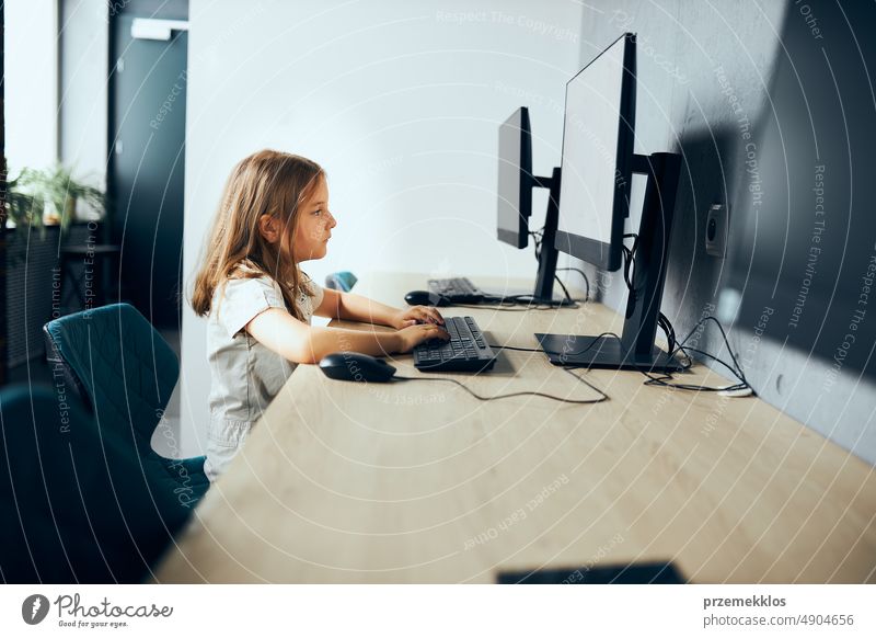 Gelangweiltes Schulmädchen sitzt am Schreibtisch im Computer-Klassenzimmer in der Schule. Das Kind ist nicht daran interessiert, den Computer zu benutzen. Langweiliger Unterricht