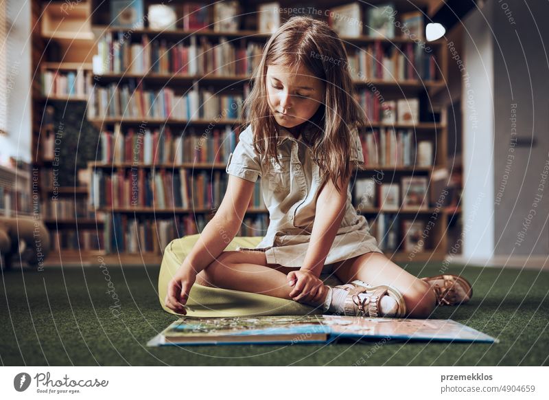 Kind löst Rätsel in Buch in Schulbibliothek. Grundschülerin beschäftigt sich mit Buch mit Rätseln. Kluges Mädchen, das lernt, Probleme zu lösen. Vorteile der täglichen Praxis