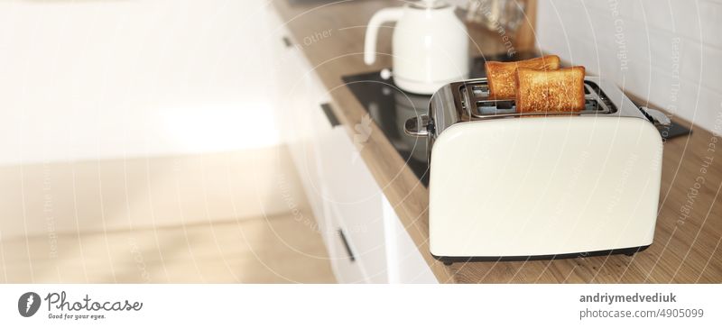 Banner der modernen weißen Toaster und geröstete Brotscheiben Toasts innen auf Holztisch in der Küche. Kopie Raum Frühstück Lebensmittel gebraten Vorrichtung