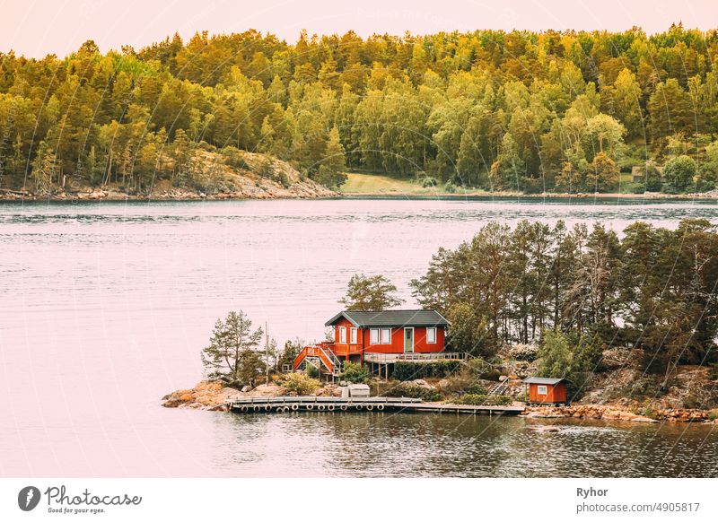 Schweden. Viele schöne rote schwedische Holzblockhaus Haus auf Rocky Island Küste im Sommer. See oder Fluss Landschaft Schwedisch Appartement Inselgruppe