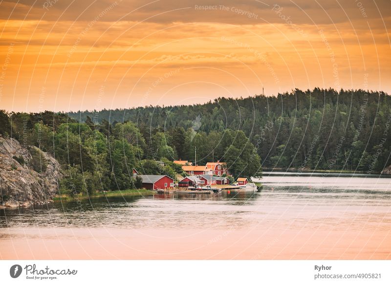 Schweden. Viele schöne rote schwedische Holzblockhäuser Häuser auf Rocky Island Küste im Sommer Abend. See oder Fluss Landschaft Schwedisch Appartement