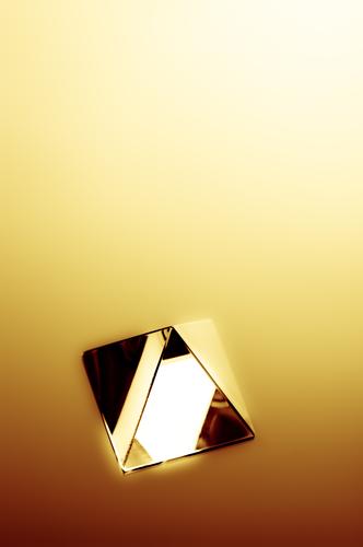 Abstraktes Bild einer Kristallpyramide mit goldgelben Strahlen aus hellem Licht. 3d abstrakt Unschärfe verschwommen Konzept konzeptionell Kondenswasser