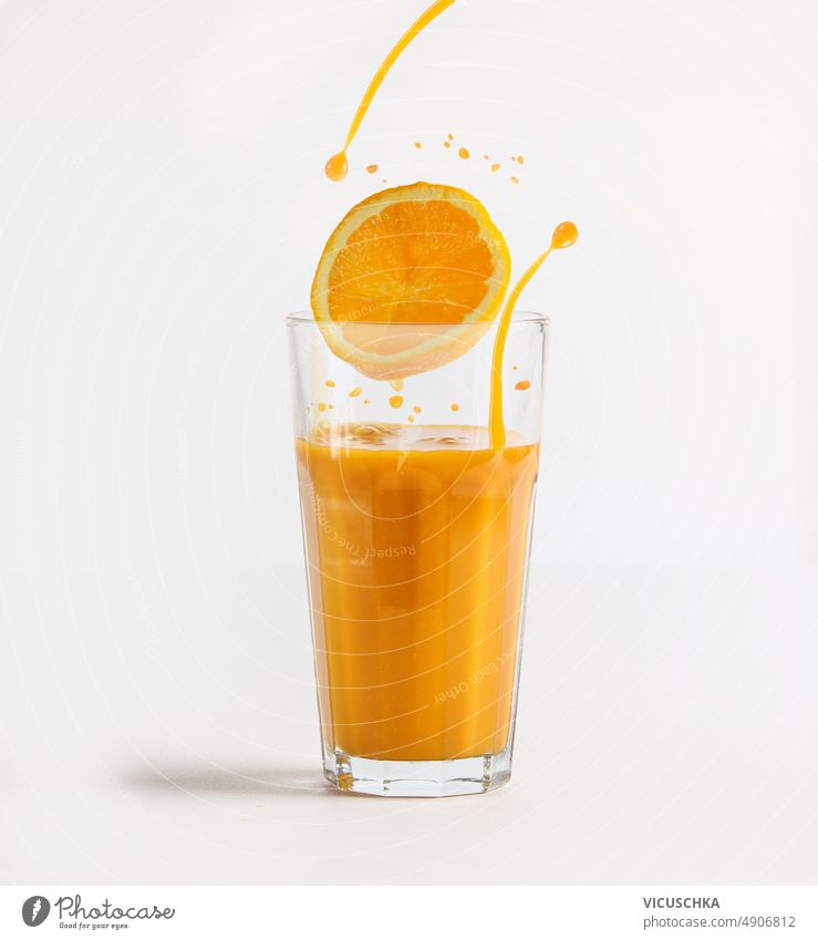 Orangensaft im Glas mit Orangenscheibe und spritzender Flüssigkeit auf weißem Hintergrund. Geplätscher liquide weißer Hintergrund Gesundheit erfrischend Getränk