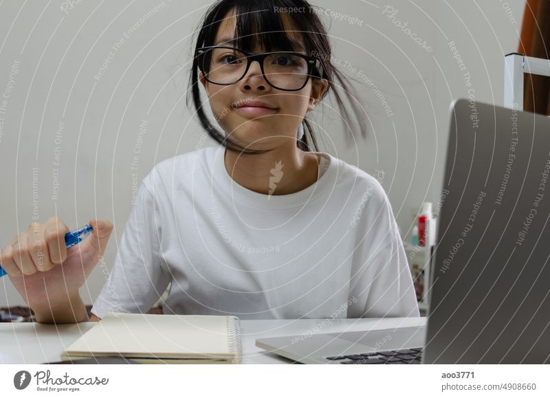 Mädchen hält Stift schreiben Buch Studie Lernen digitales Internet Video Online Computer Laptop zu Hause. online Schüler Bildung lernen Kind Hausaufgabe Person