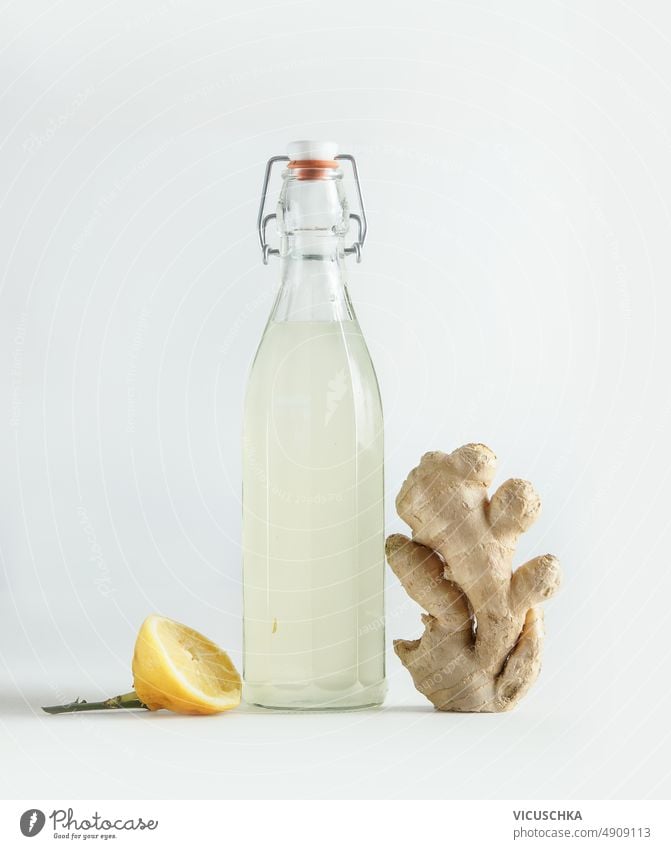 Flasche mit hausgemachtem Ginger Ale, Zitrone und Ingwerwurzel auf weißem Hintergrund weißer Hintergrund selbstgemacht Vorderansicht fermentiert Gesundheit Bier