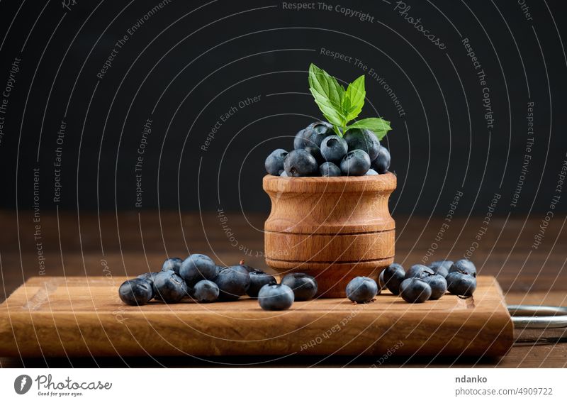 Reife Blaubeeren in einer Holzschale auf dem Tisch, schwarzer Hintergrund Lebensmittel frisch Frucht roh reif Nahaufnahme blau saftig Vegetarier Beeren süß