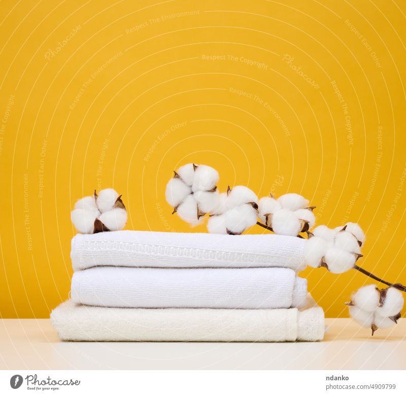 Gedrehte weiße Frotteehandtücher auf weißem Tisch, gelber Hintergrund Sauberkeit Handtuch baden Regal Innenbereich Bad weich Pflege Spa Design heimwärts Körper