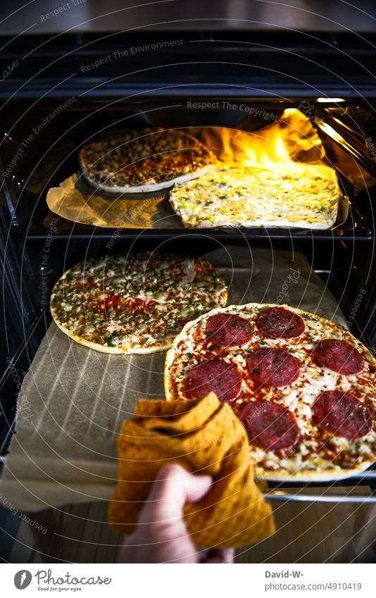 Fertigpizza aus dem Ofen herausnehmen Pizza Fastfood ungesund Hand zubereiten ungesunde Ernährung Lebensmittel