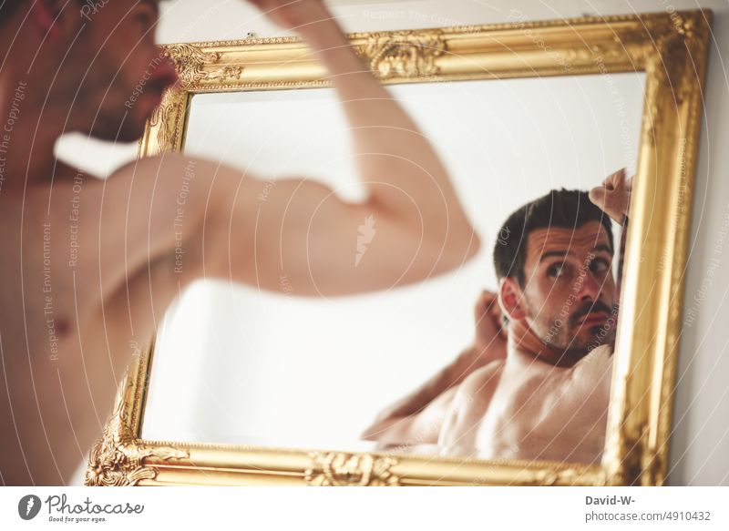Mann betrachtet sich im Spiegel Spiegelbild selbstkritisch posen betrachten Muskel Selbstbewusstsein beobachten Blick Körper eitel anspannen sexy