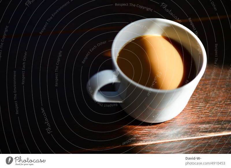 eine Tasse mit Kaffee im Sonnenlicht Becher ruhe Sonnenstrahlen Morgenroutine Kaffeepause Kaffeetasse Lichterscheinung Schatten Tisch
