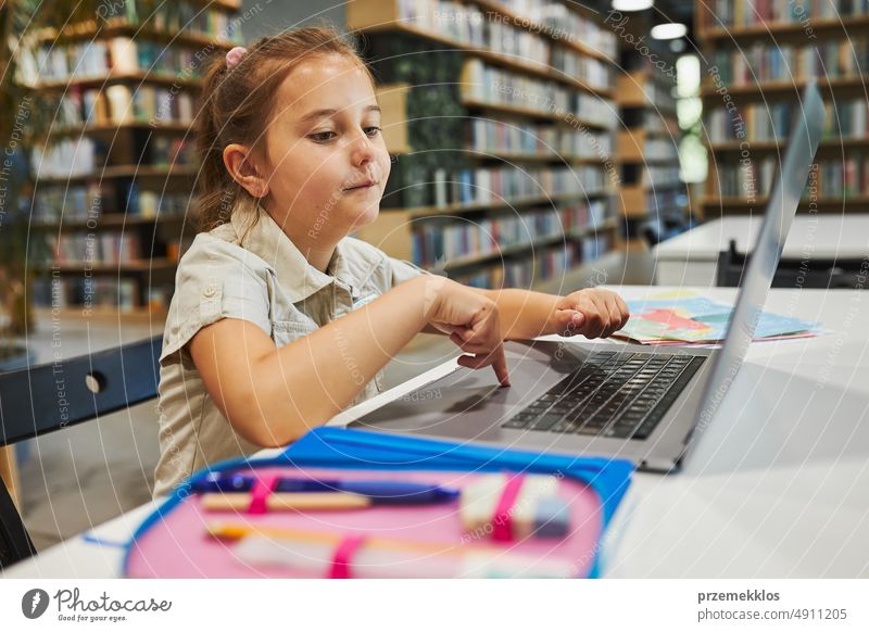 Engagierte Schülerin macht ihre Hausaufgaben mit dem Laptop in einem Club nach der Schule in der Grundschule. Zurück zur Schule. Kind nutzt Technologie im Informatikunterricht. Kluges Mädchen lernt von Bildungsanwendung in der Schule