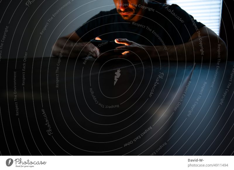 Mann am Handy dunkel Sucht Hände anonym Tisch sitzen benutzen Strahlung Abhängigkeit düster