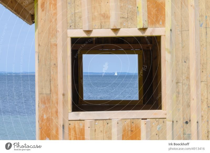 Blick durch eine alte Holzhütte in einen Fensterrahmen mit Segelschiff und Meer hindurch ungewöhnlich Rahmen eingerahmt
