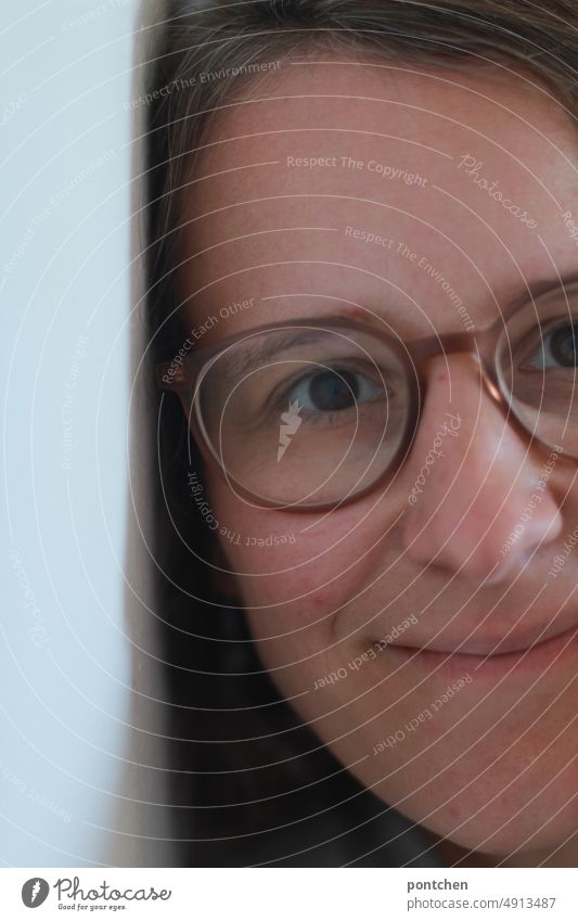 Gesicht einer lächelnden frau mit Brille, die an einer Mauer lehnt Frau brille mauer anlehnen gesicht Erwachsene Porträt Zufrieden Anschnitt Zuhause innenraum