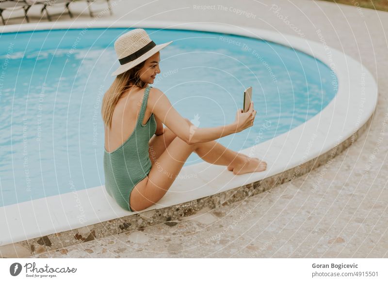 Junge Frau sitzt am Swimmingpool und nimmt Selfie-Foto mit Handy im Haus Hinterhof Bikini Kaukasier Tag genießend Außenseite frisch Feiertag heimwärts Freizeit